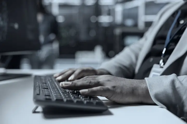 Technician typing at a keyboard in a server room